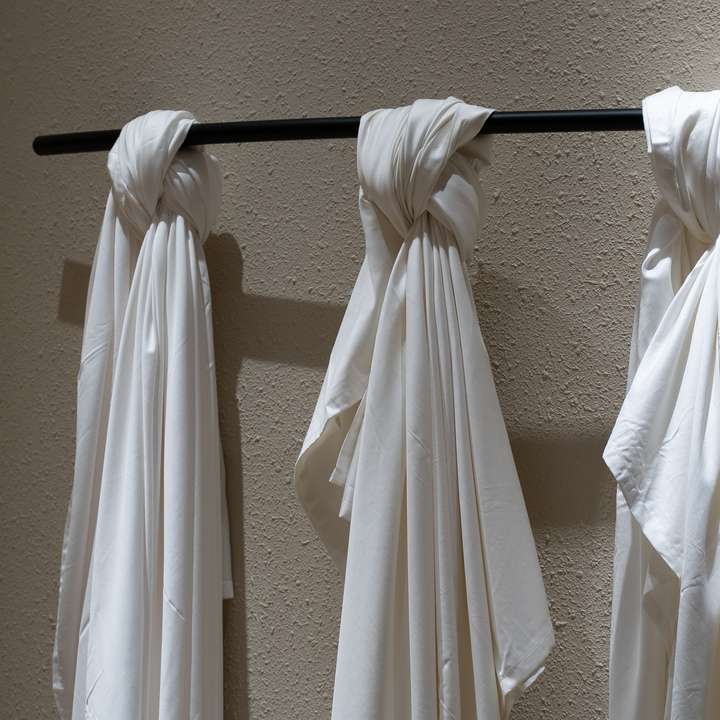 White cloth knotted by hand onto a black rod